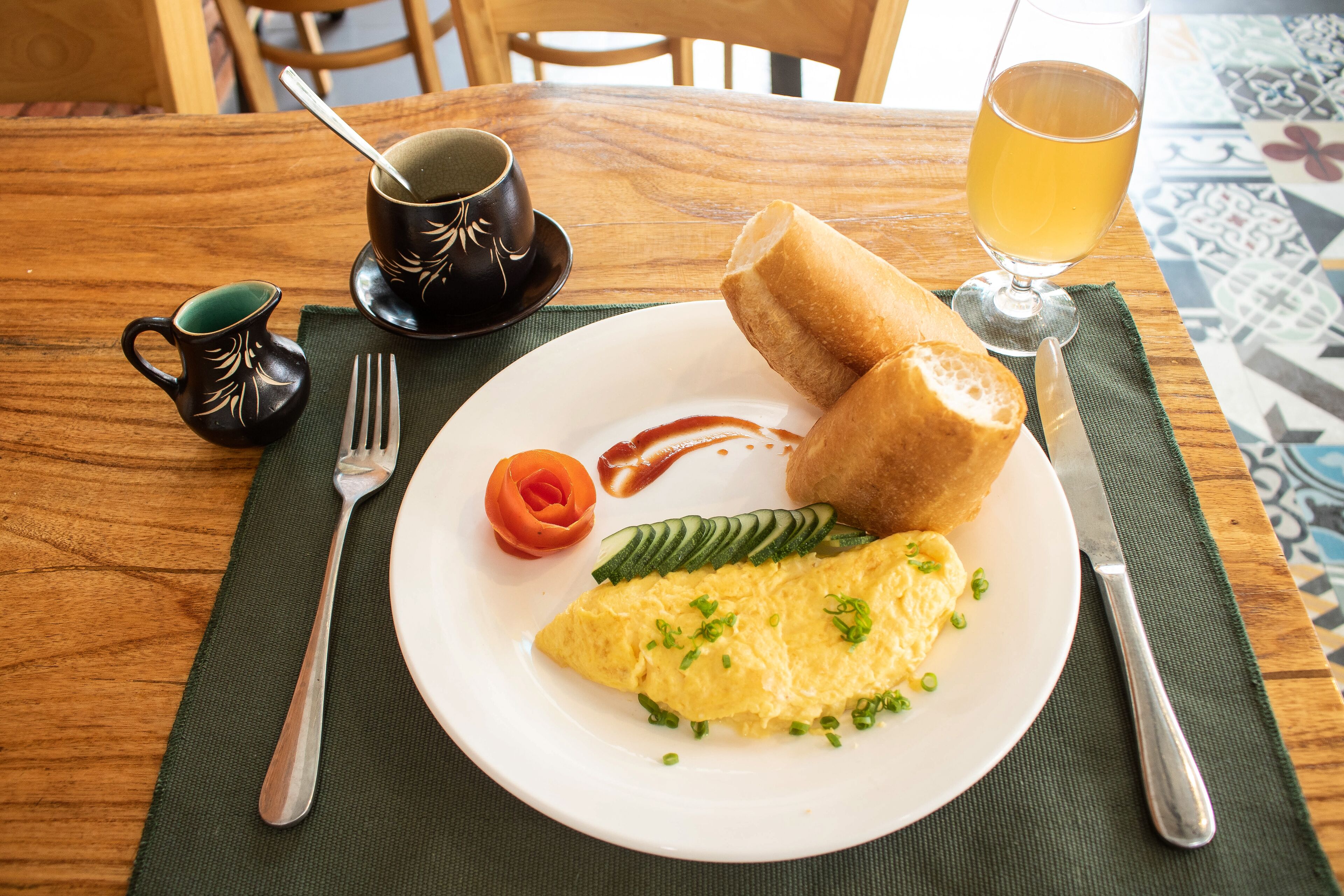 A breakfast plate with an omelet, bread, and vegetables on a wooden table.