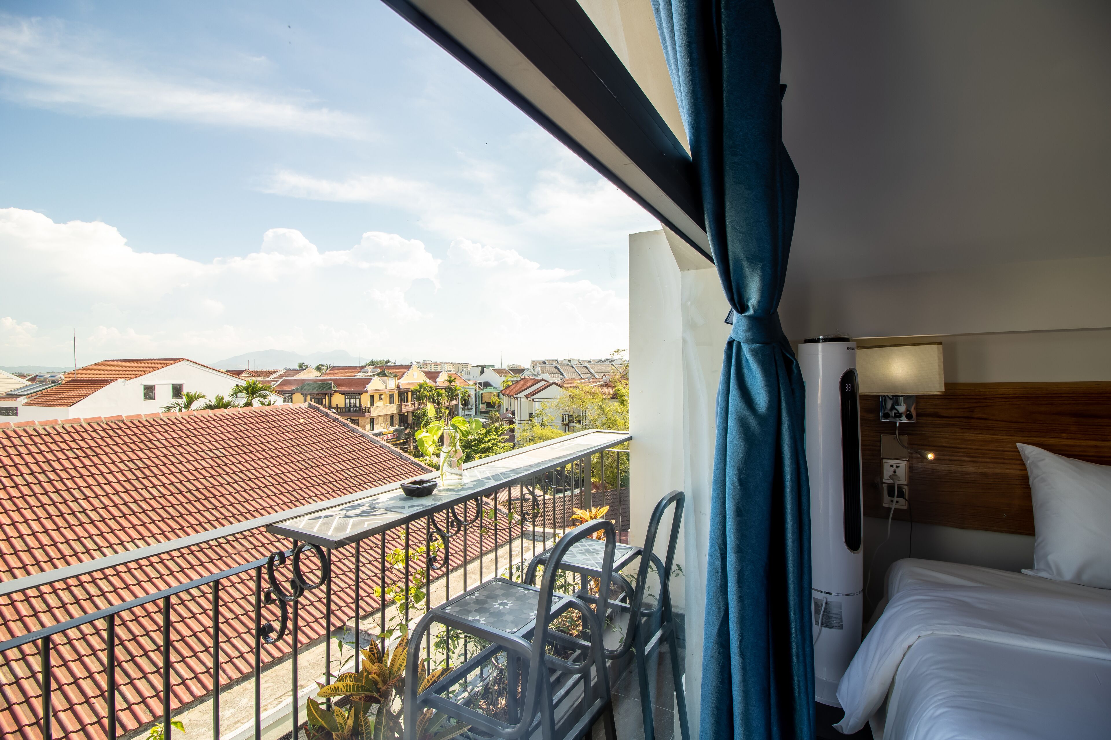 A hotel room with a balcony, a bed, a table, and chairs.