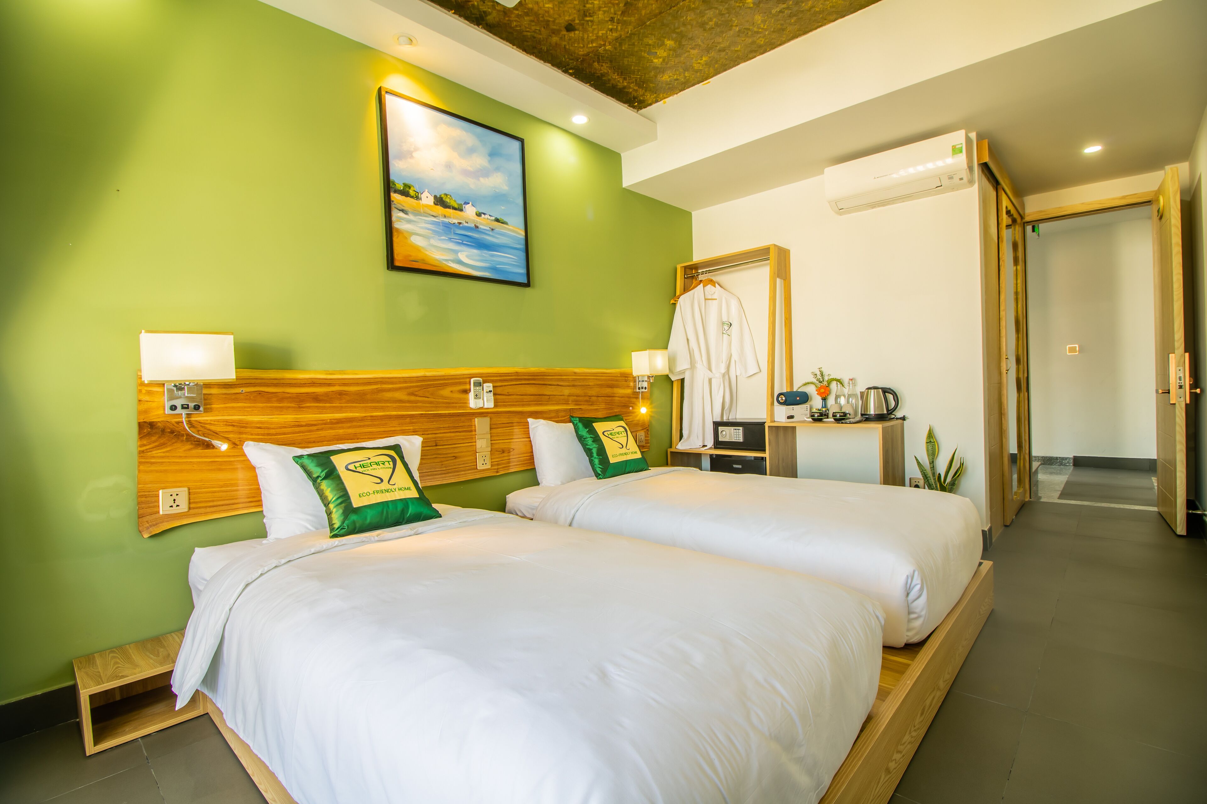 A hotel room with two beds, a wooden headboard, a painting on the wall, and a bathroom visible through an open door.
