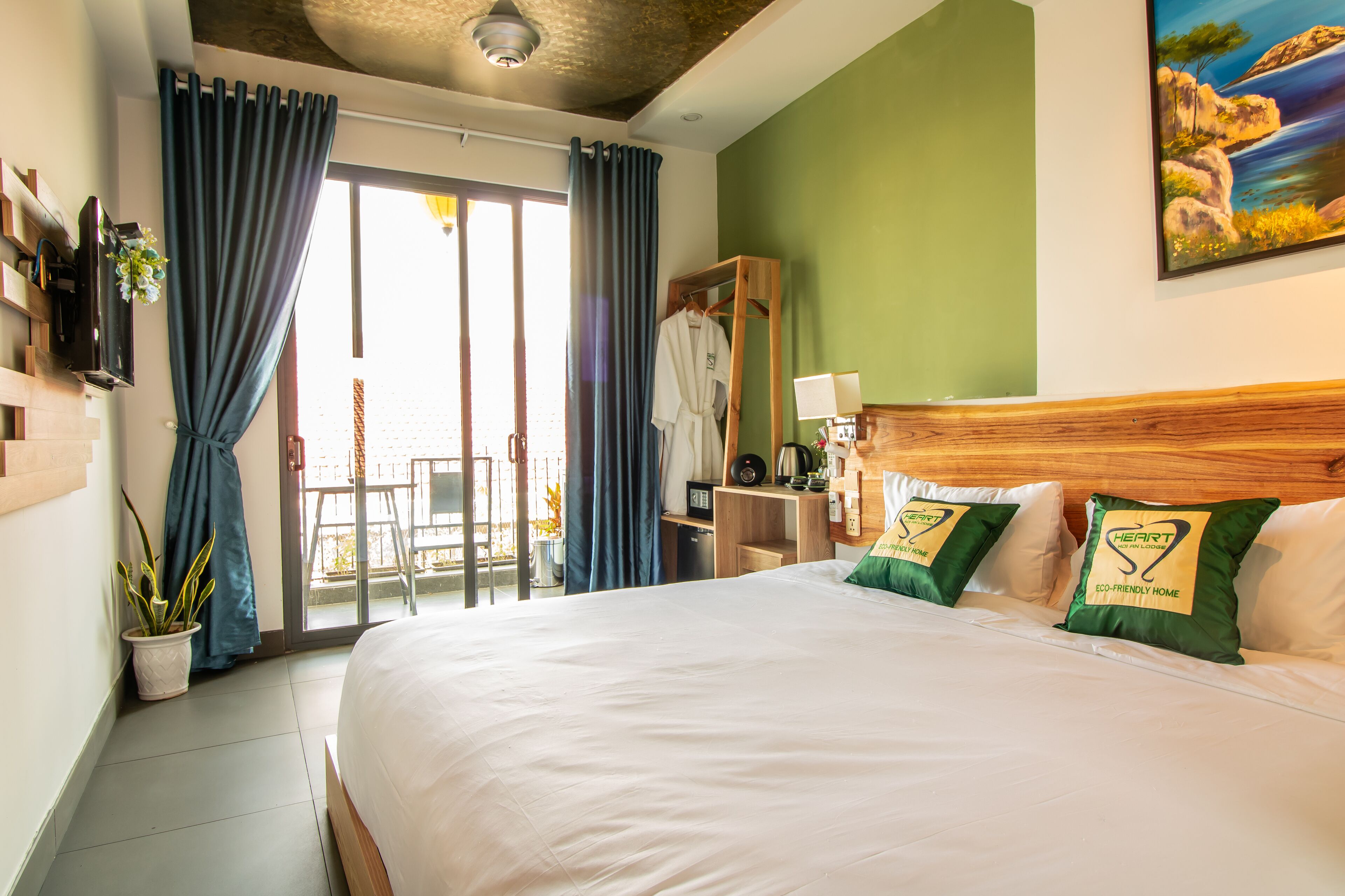 Une chambre d’hôtel avec un grand lit, une tête de lit en bois, un mur vert, un tableau et un balcon avec une chaise.