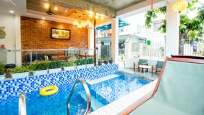 Una piscina con borde de mosaico azul, un flotador amarillo y una escalera de metal.