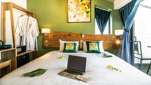 Una habitación de hotel con una cama, una computadora portátil, un teléfono y una bata en un perchero.
