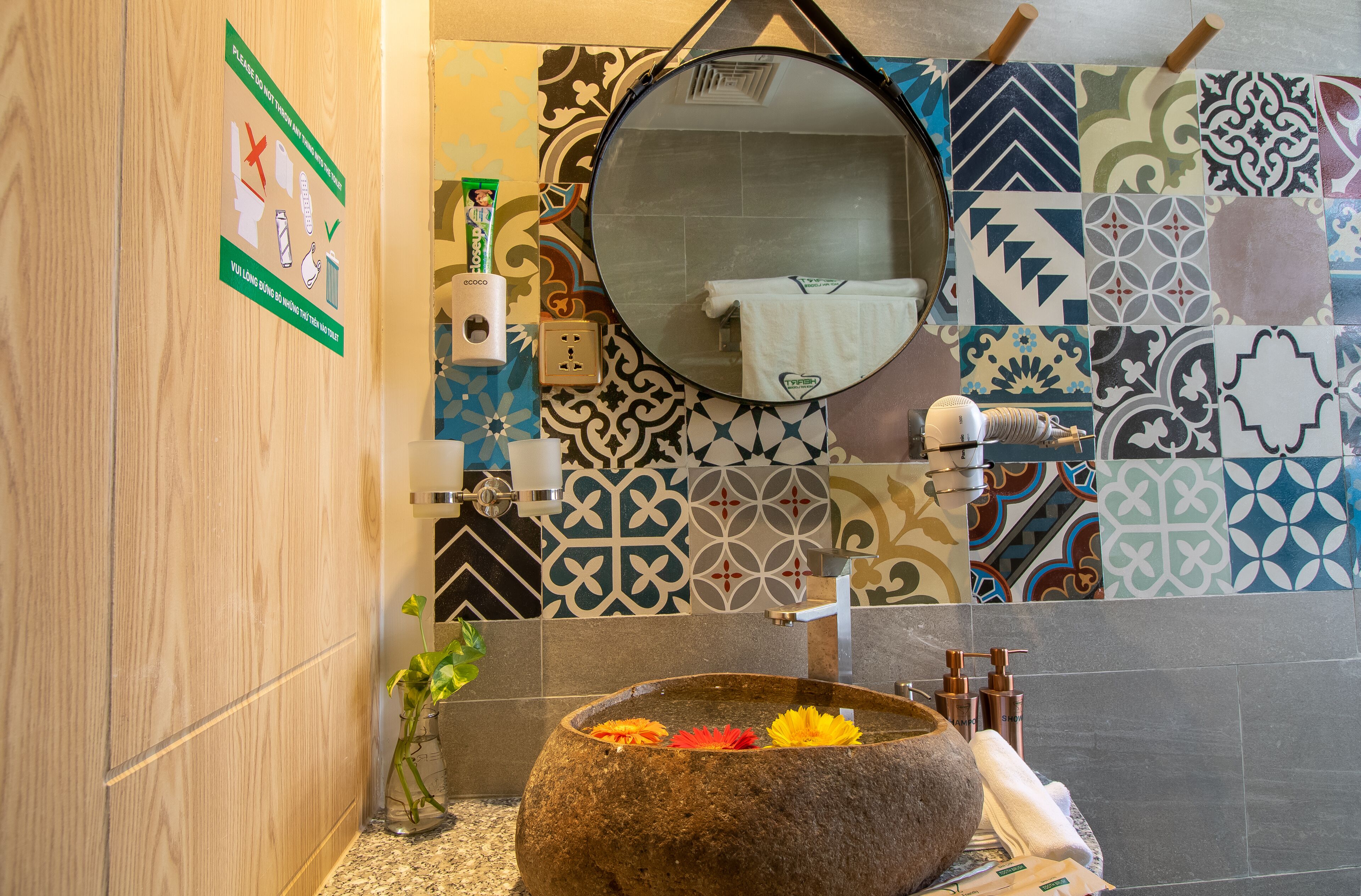 A bathroom with a stone basin, a mirror, a towel, and a hand dryer.