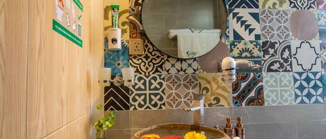 A bathroom with a stone basin, a mirror, a towel, and a hand dryer.