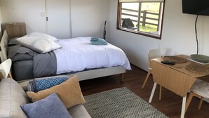 Una camera da letto con un letto, una scrivania, una sedia, una TV e una finestra vista all'esterno.