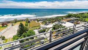 A coastal view from a balcony overlooking a beach with a parking area, a playground, and a building with a sloped roof. - Seaview Villa Coastal Estate (Shoufeng)