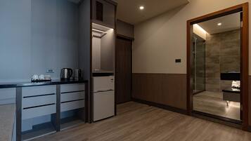 A compact kitchen with a built-in refrigerator, a coffee maker, and a kettle on the counter.