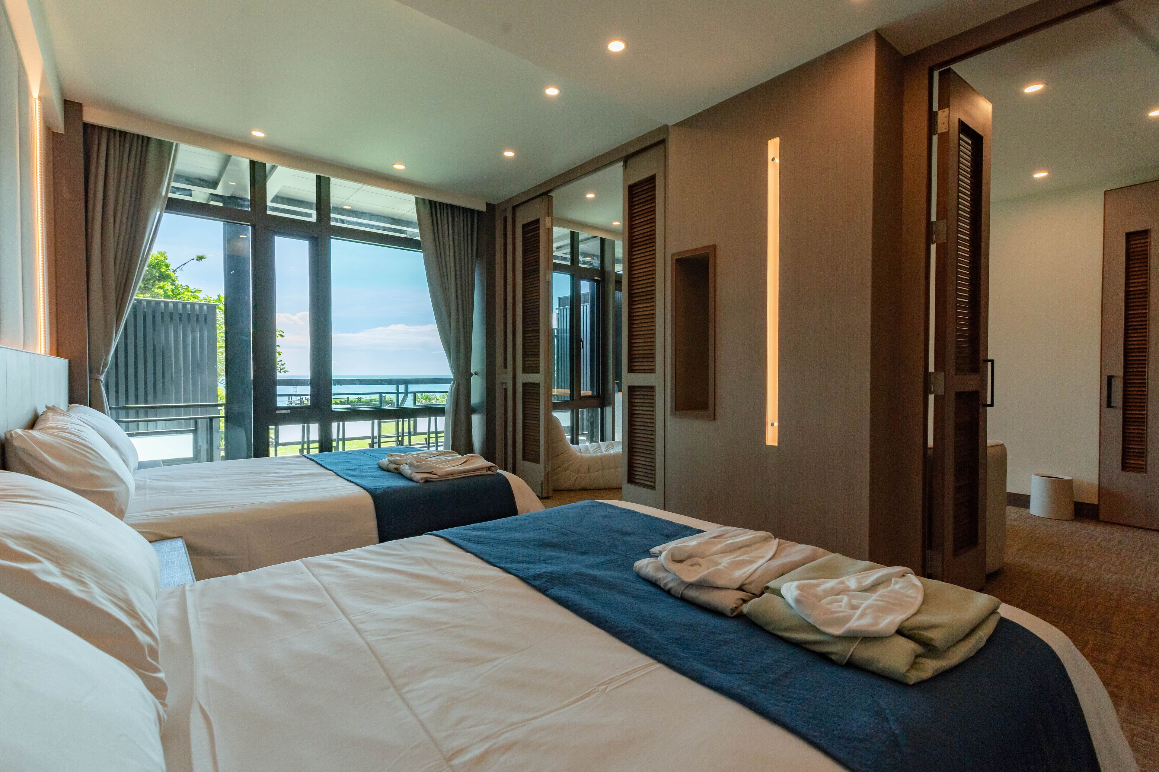 A hotel room with two beds, a balcony, and a view of the sea.