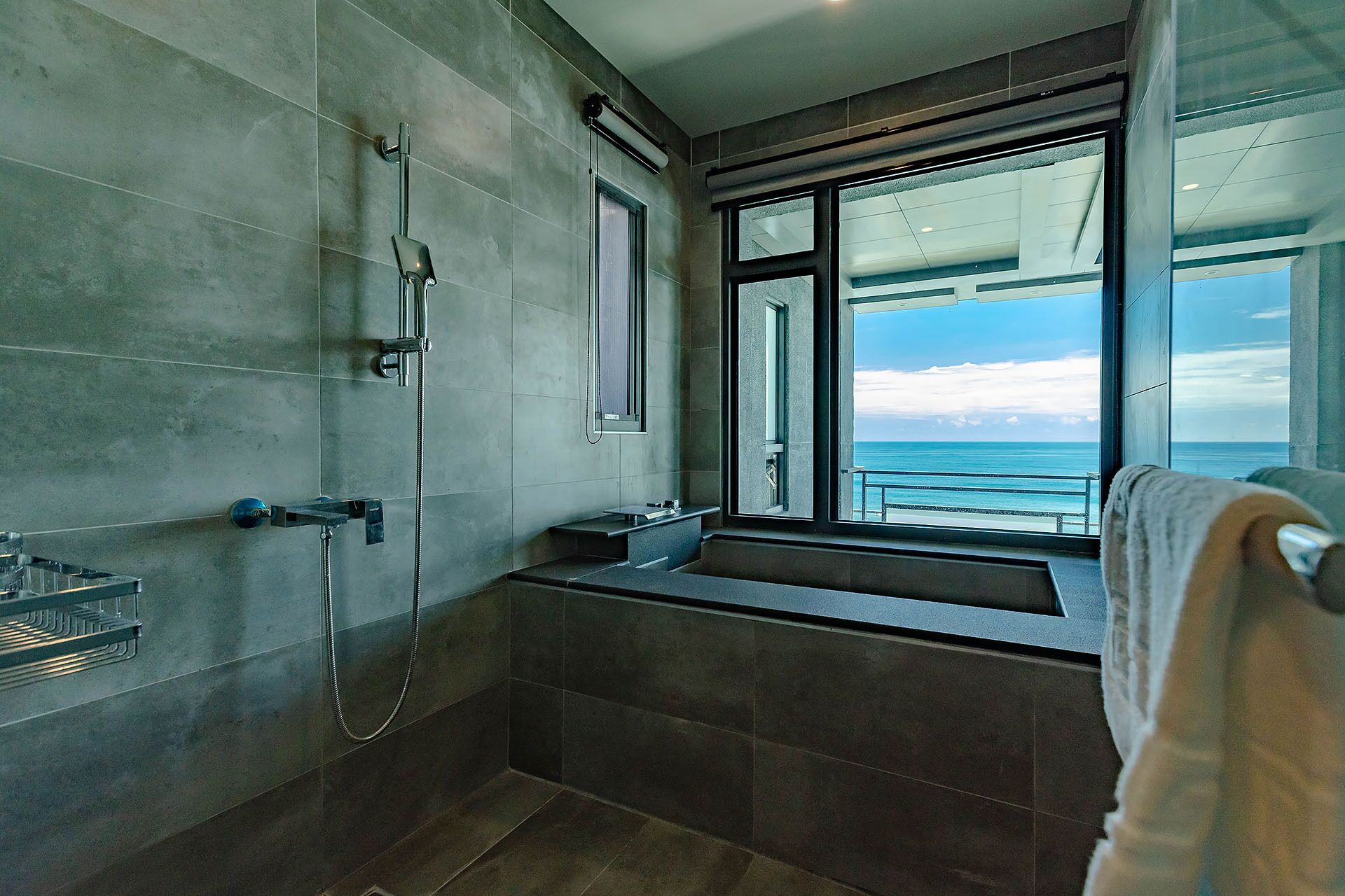 A modern bathroom with a large window offering a view of the sea.
