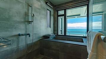 A modern bathroom with a large window offering a view of the sea.