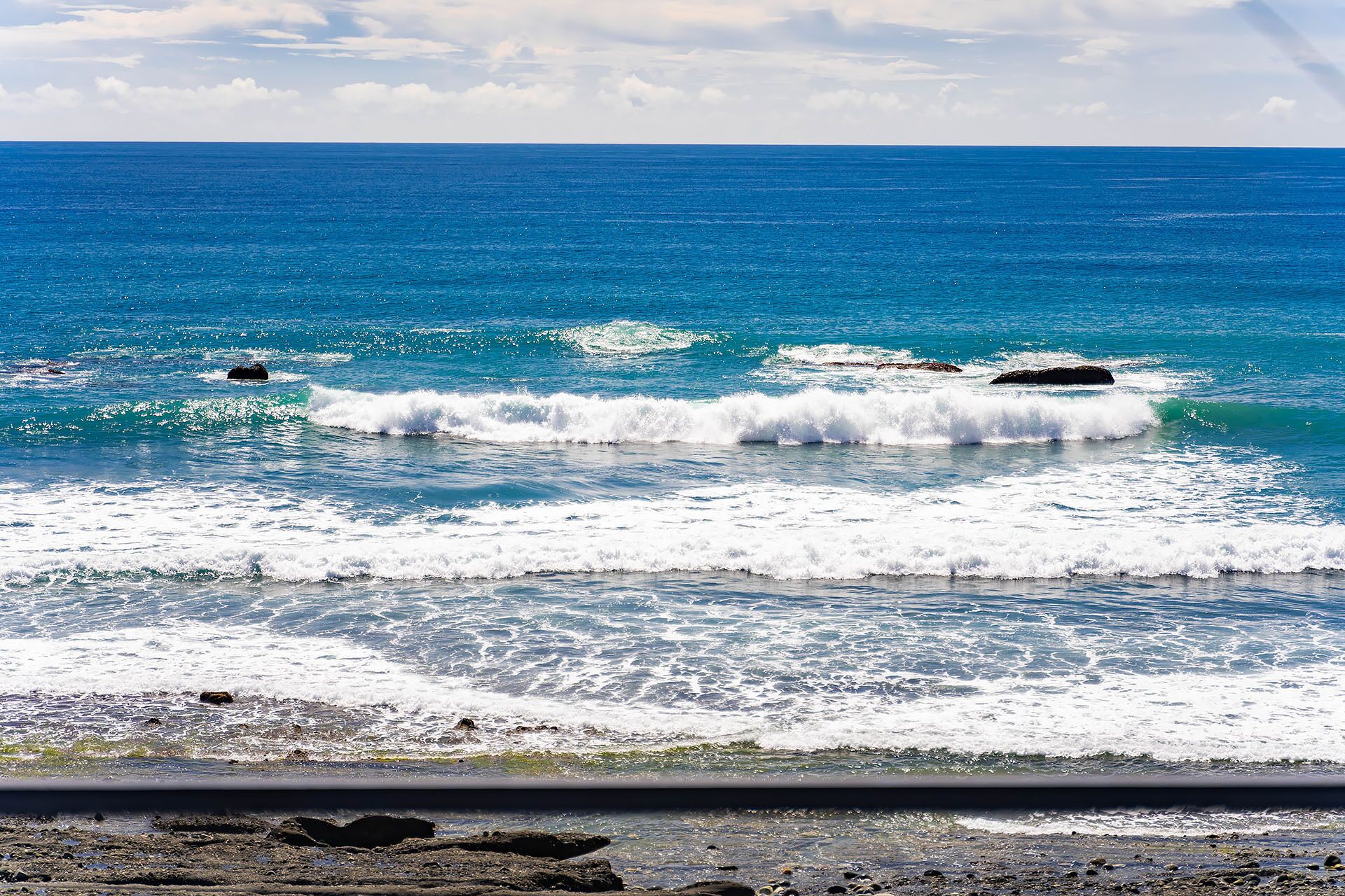 A coastal scene with waves crashing onto a rocky shore.