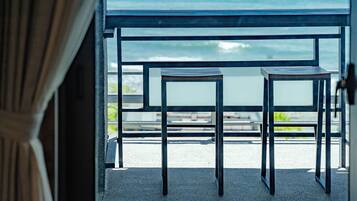 A balcony with two metal tables and chairs, overlooking a body of water.