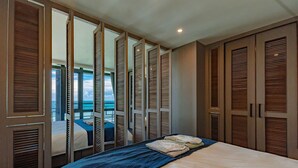 A bedroom with a bed, a blue blanket, and wooden closets with louvered doors. - Seaview Villa Coastal Estate (Shoufeng)