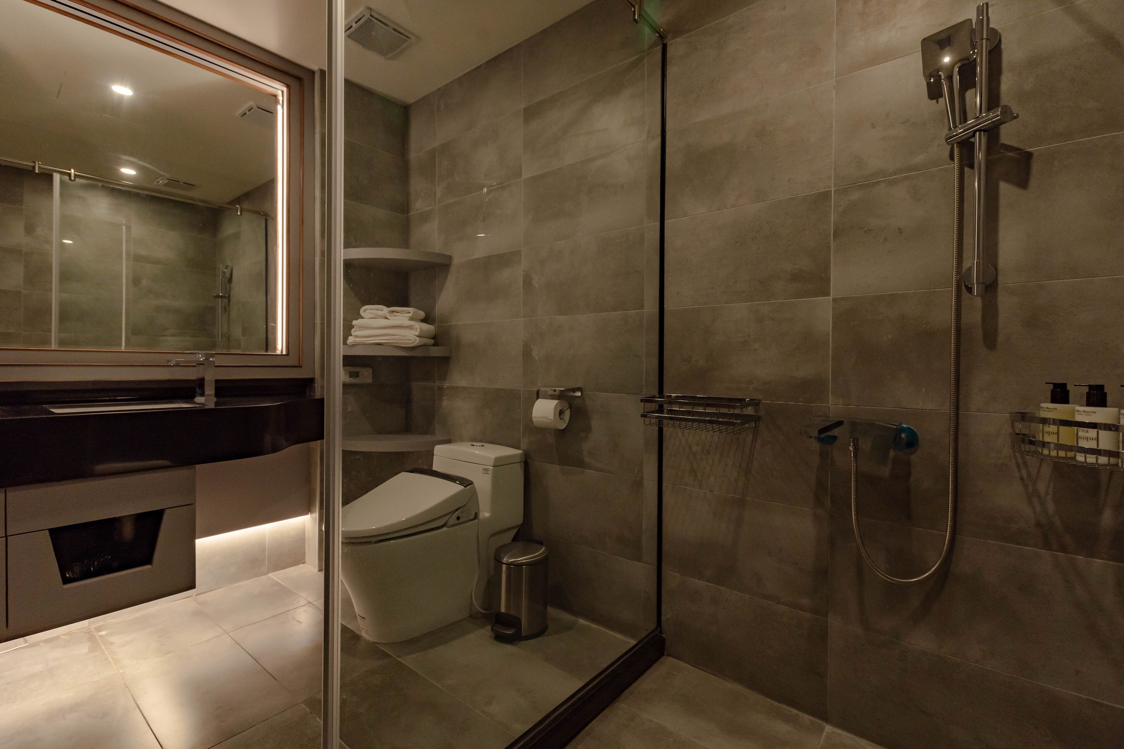Ein modernes Badezimmer mit Duschkabine aus Glas, Toilette und Waschbecken mit Waschtisch.