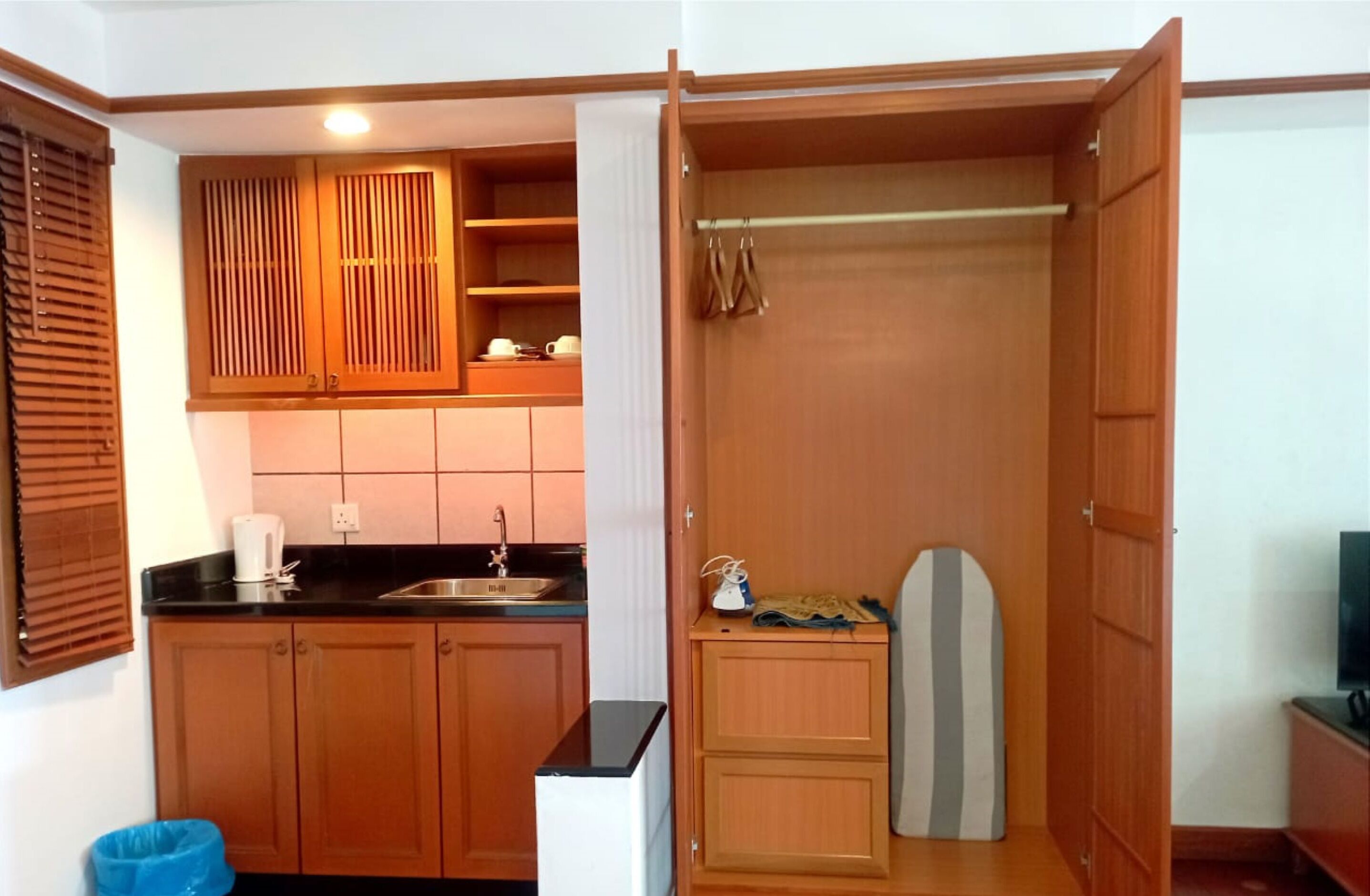 Una cocina compacta con armarios de madera, una encimera negra y un lavabo.