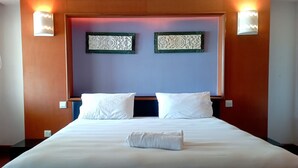 Ein Hotelzimmer mit einem großen Bett, zwei Wandleuchten und zwei dekorativen Wandpaneelen.