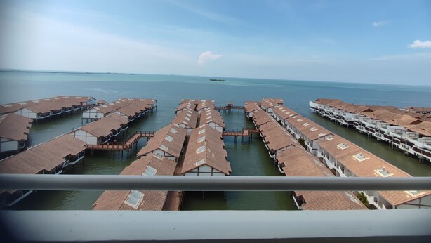 Blick auf überwasserbungalows mit mehreren Ebenen, die durch Wege miteinander verbunden sind, mit freiem Blick auf den Ozean.