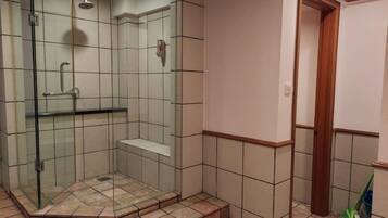 A shower with a glass door, a bench, and a tiled floor.