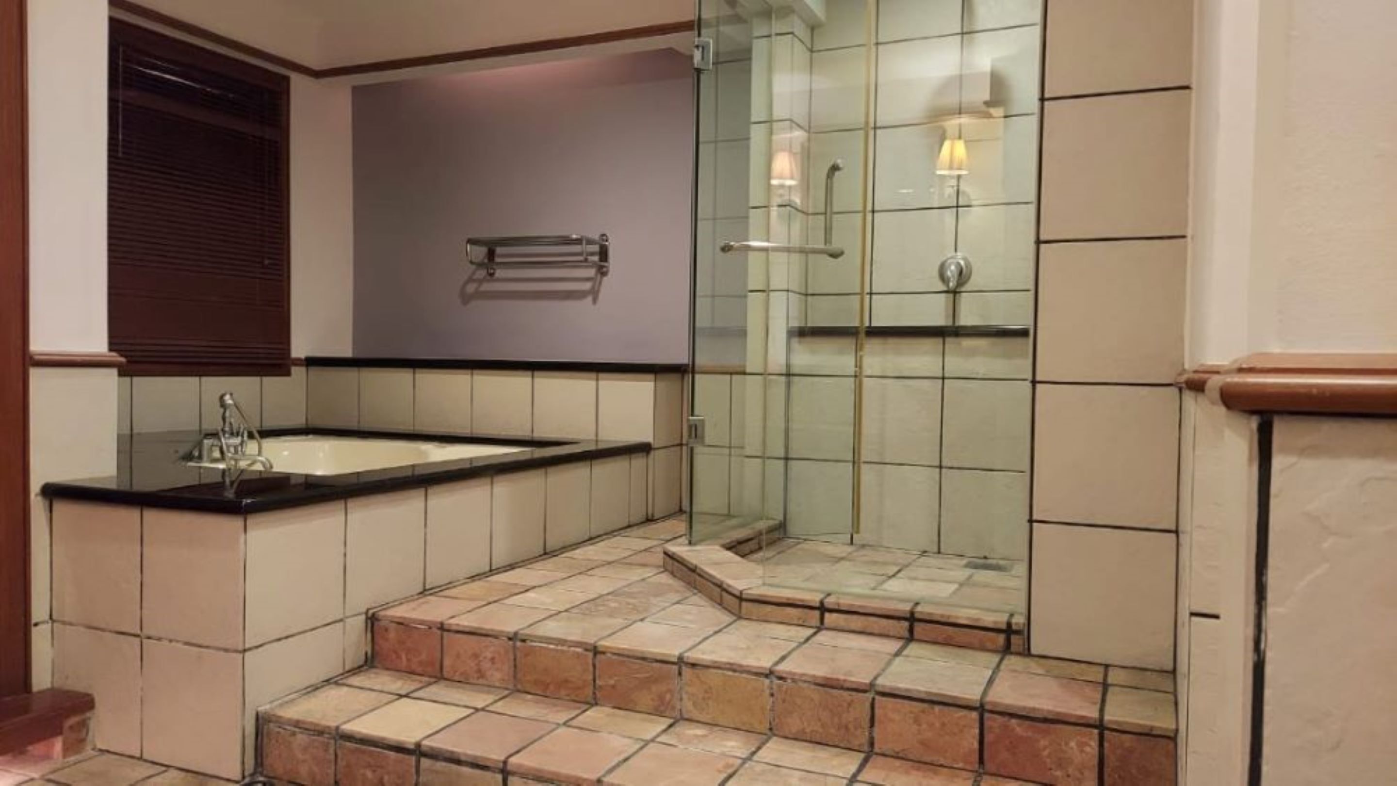 Ein Badezimmer mit Badewanne, Duschkabine aus Glas und Fliesenboden.