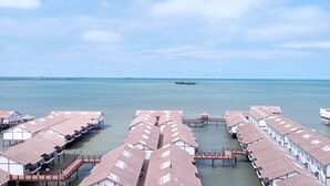 Eine Reihe von überwasserbungalows mit freiem Blick auf das Meer und einer kleinen Insel in der Ferne.