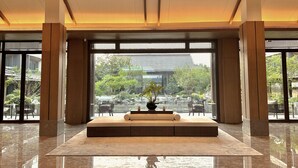 A spacious lobby with a large seating area, a view of the garden, and a traditional architectural style. - Blue City Fenghe Resort Hotel (Jiaxing)