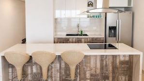 A modern kitchen with a white countertop, stainless steel appliances, and a wooden backsplash. - Luxury Beachfront Apartment in Chipipe – Stunning Views & Top Amenities (Salinas)