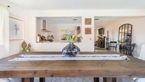 Ein Essbereich mit Holztisch, Blumen in einer Vase und Blick in die Küche.