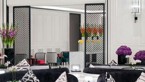 A modern, multi-level living area with black and grey sofas, a dining table, and a balcony with blue chairs. - Tonino Lamborghini Rosso HangZhou (Suzhou)