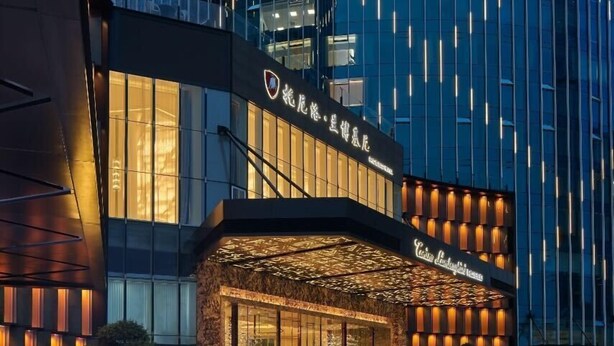 A modern hotel with a glass facade, a well-lit entrance, and a paved courtyard. - Tonino Lamborghini Rosso HangZhou (Suzhou)