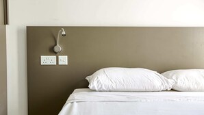 A hotel room with a bed, white pillows, a headboard, and a wall-mounted light fixture. - Gzira Suite 14 (Gzira)