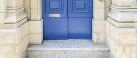A blue double door with a keypad lock, set in a stone building with a small set of steps leading up to it.