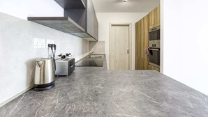A modern kitchen with a grey marble countertop, stainless steel appliances, and a wooden cabinet. - Gzira Suite 14 (Gzira)