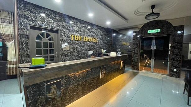 A hotel reception area with a marble wall, a reception desk, and a sign that reads "THE HOTEL."