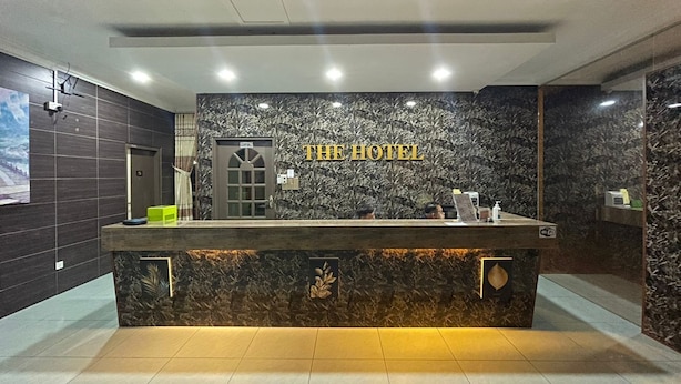A hotel reception desk with a marble wall backdrop and the hotel's name displayed above. - THE HOTEL (Sandakan)
