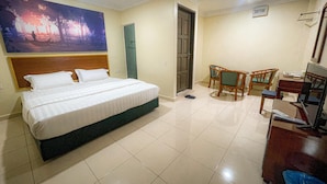 A hotel room with a large bed, a desk with a chair, a television, and a painting on the wall. - THE HOTEL (Sandakan)