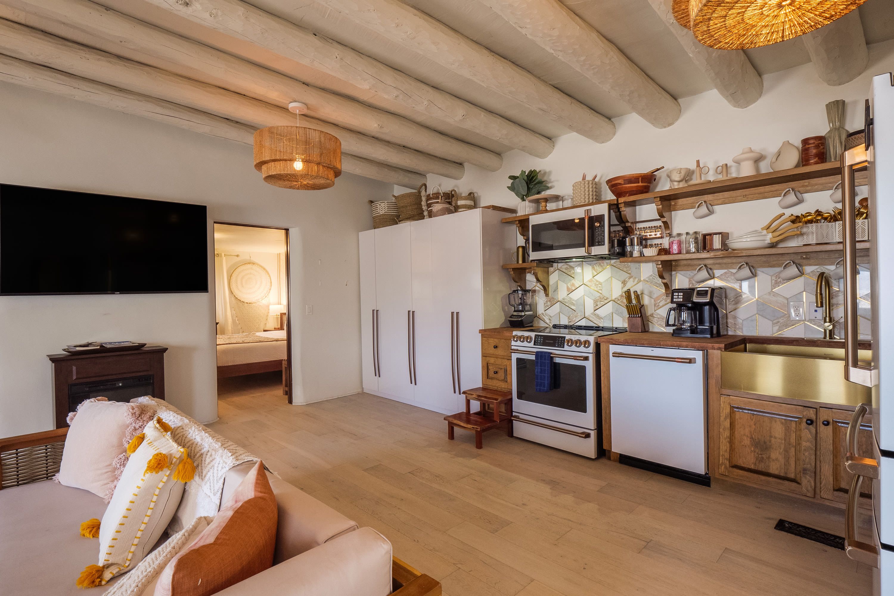 Une cuisine moderne dotée d’un four, d’un micro-ondes et d’un évier encastrés, de meubles de rangement en bois et d’un luminaire suspendu.