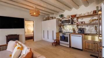 A modern kitchen with a built-in oven, microwave, and sink, wooden cabinets, and a hanging light fixture.