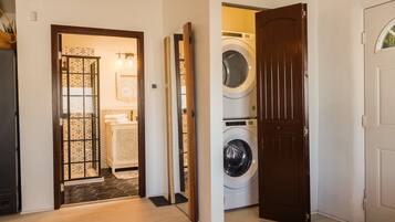 A laundry room with two washing machines and a door leading to a bathroom.
