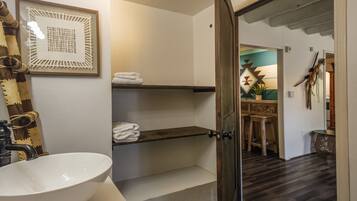 A bathroom with a white sink, a towel rack, and a framed artwork on the wall.