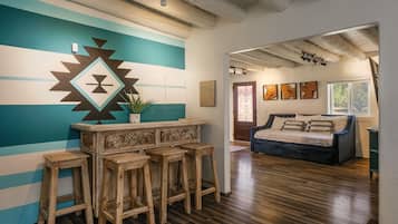 A room with a wooden bar, a bed, and a wall with geometric patterns.