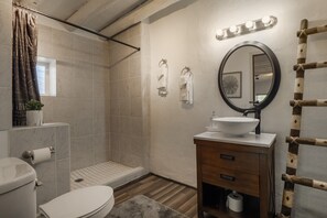 Un baño con ducha, inodoro, lavamanos y tocador.