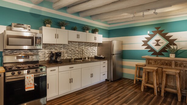 A kitchen with white cabinets, a stainless steel refrigerator, and a wooden countertop.