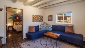 A living room with a blue sofa, patterned cushions, a wooden coffee table, and a rug with geometric designs.