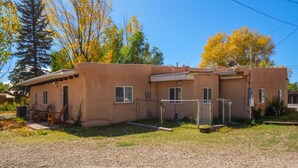 A single-story building with a flat roof, a small porch, and a fenced yard.