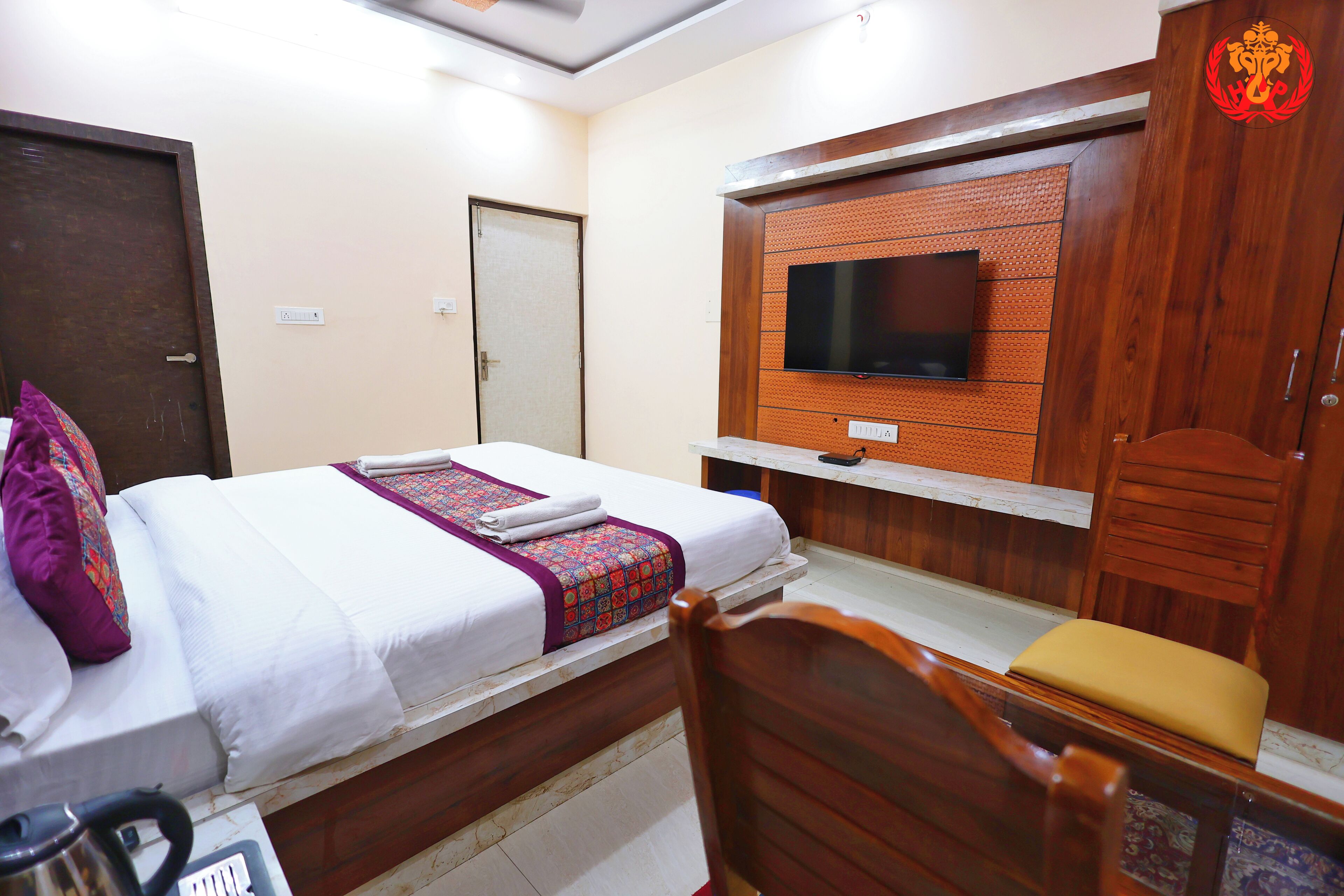 A hotel room with a bed, a television, a wardrobe, and a chair.