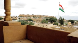 Een balkon met uitzicht op een historisch fort en een vlag.