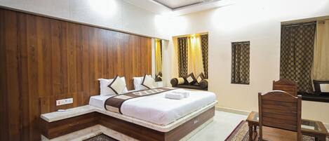 A modern hotel room with a large bed, wooden headboard, and a small table with a chair.