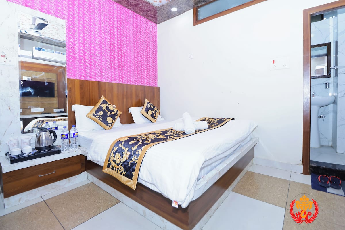 Ein Hotelzimmer mit Bett, Nachttisch und einem durch eine Glastür einsehbaren Badezimmer.