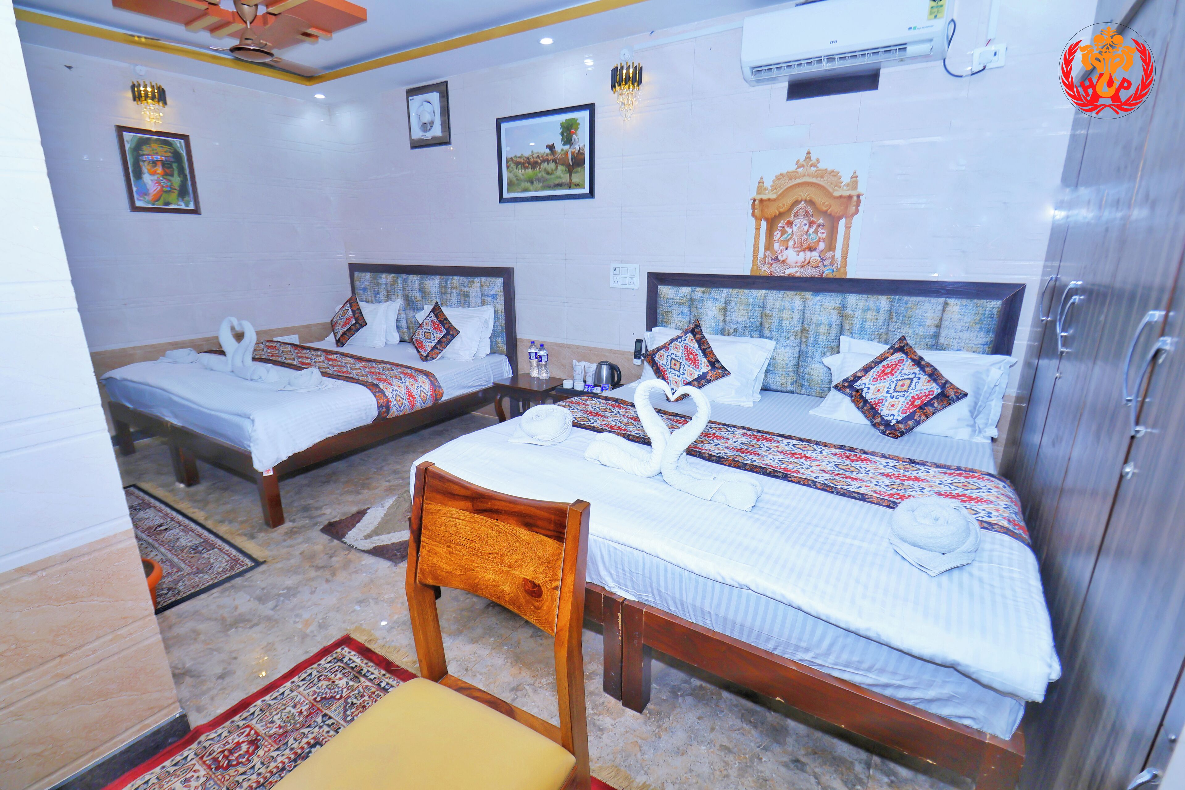 A hotel room with two beds, each with a headboard, a wooden chair, and a small table.