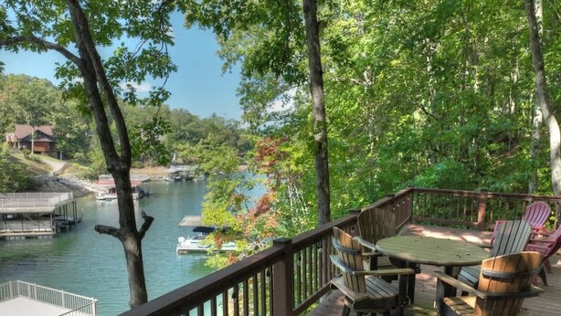 Une terrasse dotée de mobilier d’extérieur, donnant sur un plan d’eau où se trouvent des bateaux.